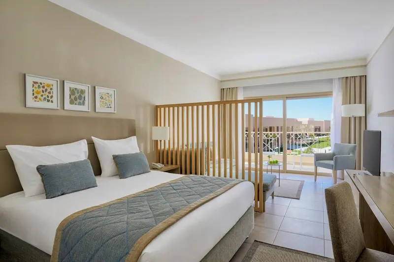 Une chambre lumineuse avec un grand lit et un coin salon.