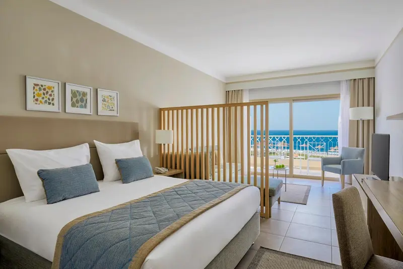 Chambre lumineuse avec un grand lit et vue sur la mer.