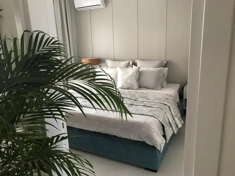 Une chambre avec un grand lit recouvert d'oreillers et d'une plante verte.