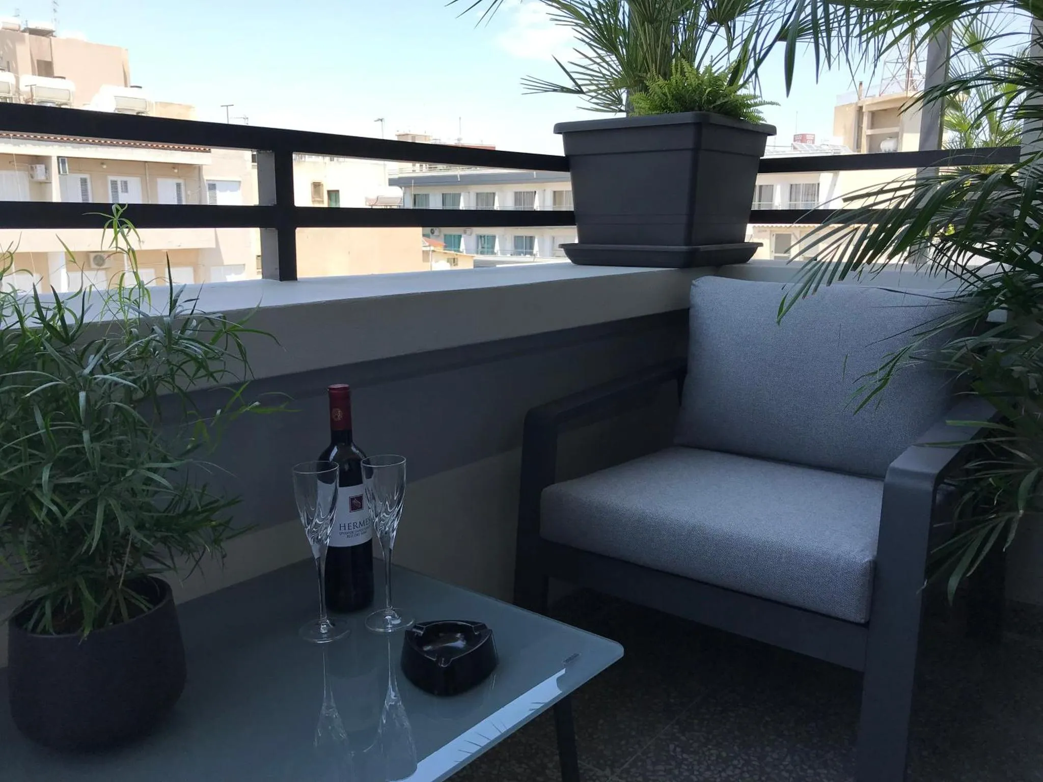 Une table basse avec une bouteille de vin et deux verres sur une terrasse.