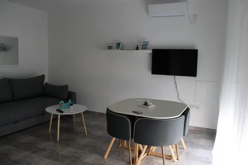 Un espace de vie lumineux avec un canapé, une table et un téléviseur mural.