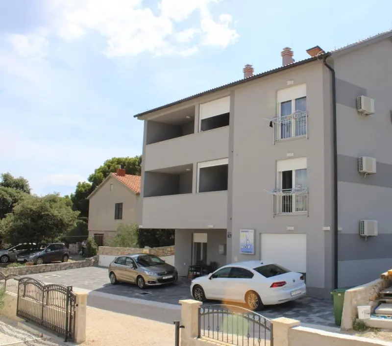 Façade d'un bâtiment à deux étages avec des balcons et un parking.