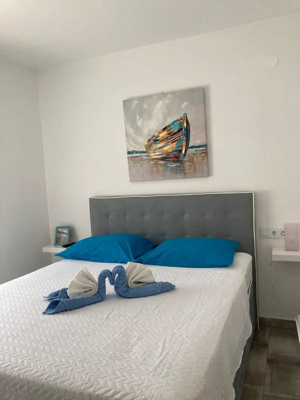 Une chambre avec un lit recouvert d'une courtepointe blanche et de coussins bleus.