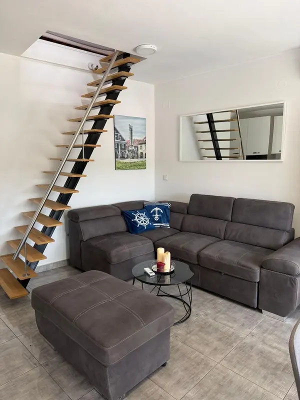 Un salon moderne avec un canapé d'angle gris et un escalier hélicoïdal.