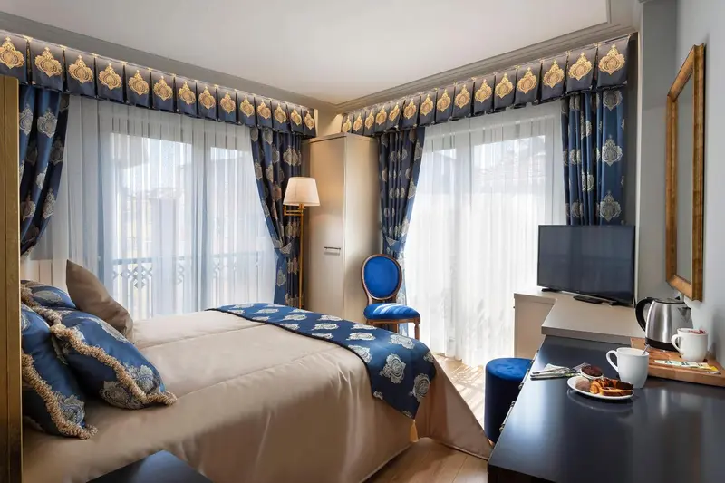 Chambre lumineuse avec un lit fait et une petite table avec un plateau de petit-déjeuner.