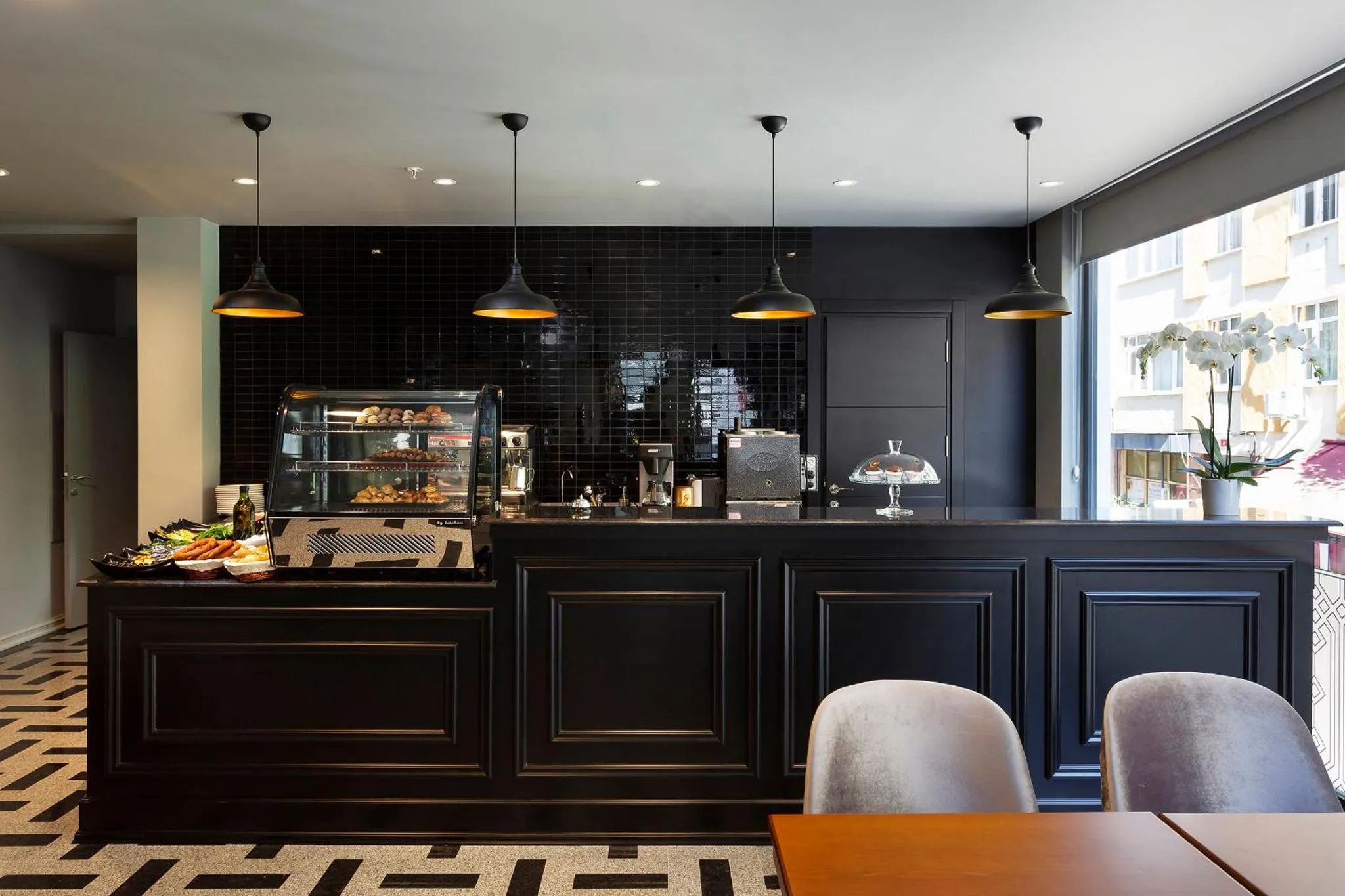 Un comptoir noir présente des pâtisseries et des boissons dans un espace lumineux.