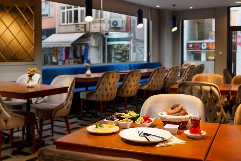 Une salle de restaurant lumineuse avec des tables dressées et un buffet de petit-déjeuner.