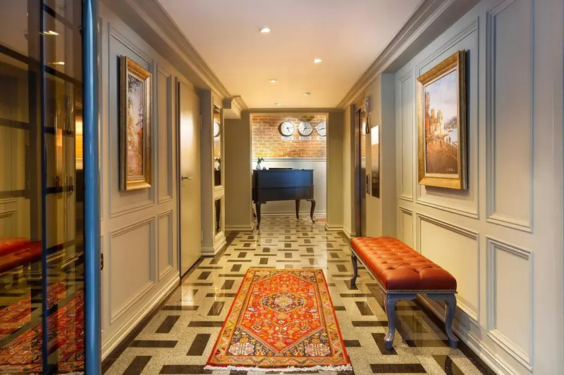 Un couloir d'hôtel décoré de tableaux et de boiseries mène à un comptoir d'accueil.