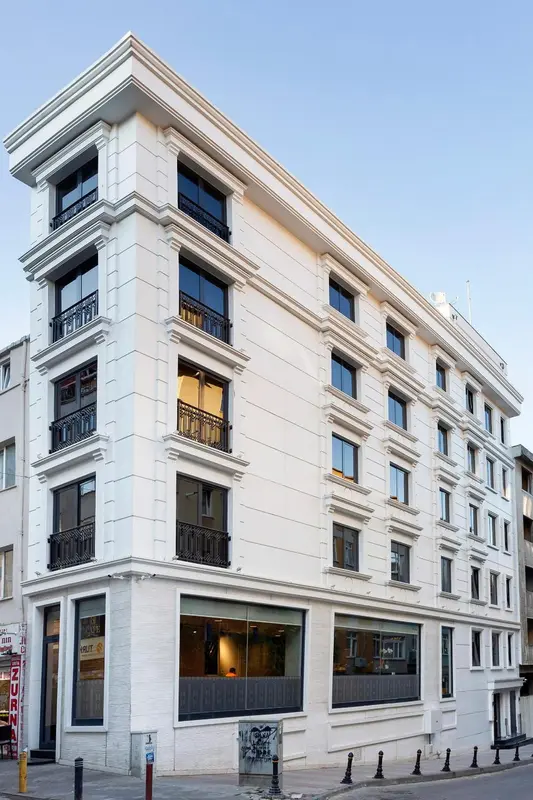 Façade blanche d'un bâtiment à plusieurs étages avec des balcons en fer forgé.
