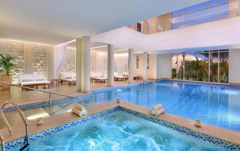 Une piscine intérieure avec un jacuzzi et des chaises longues.