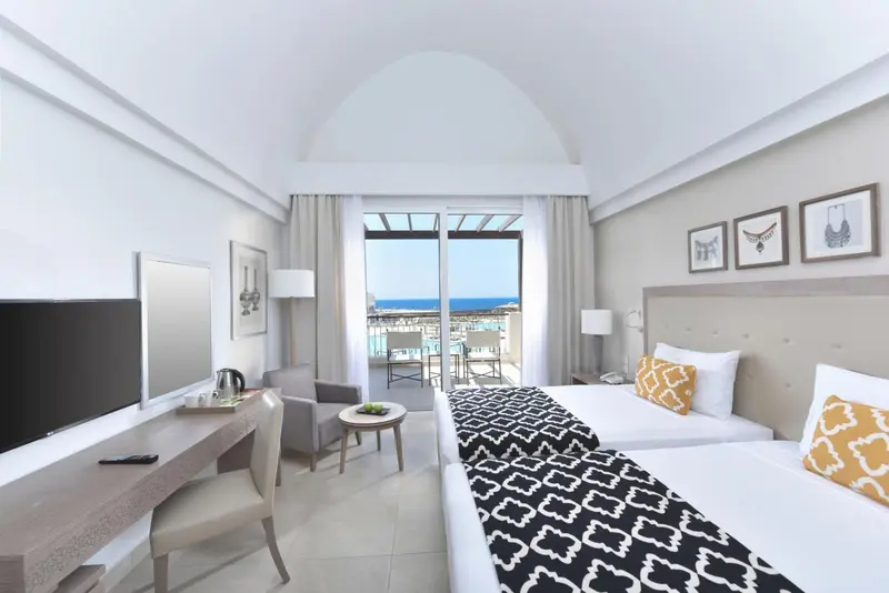 Chambre lumineuse avec un lit double et une vue sur la mer.