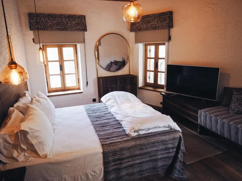 Une chambre lumineuse avec un lit fait et un miroir rond au mur.