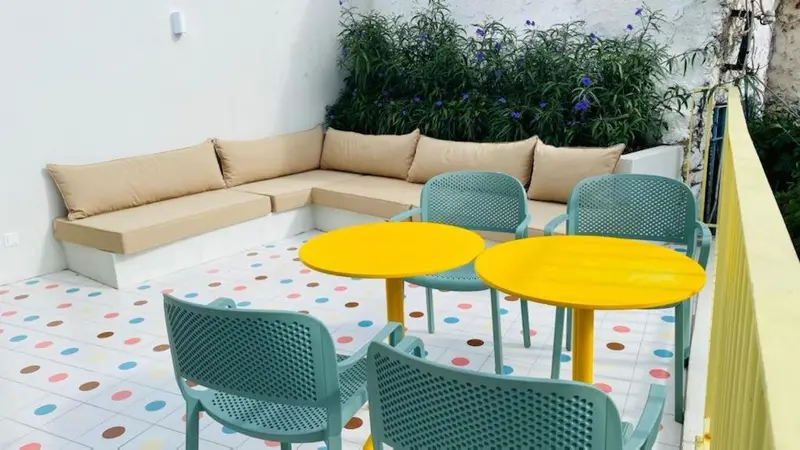 Espace de détente extérieur avec canapés et tables colorées.