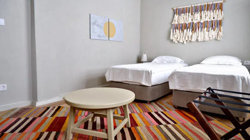 Une chambre lumineuse avec deux lits simples et une décoration murale colorée.