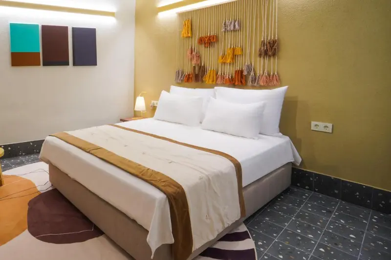 Une chambre avec un grand lit recouvert d'une courtepointe blanche et de coussins.