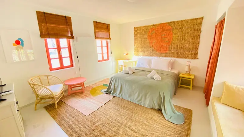 Une chambre lumineuse avec un lit recouvert d'une courtepointe verte et un tapis coloré.