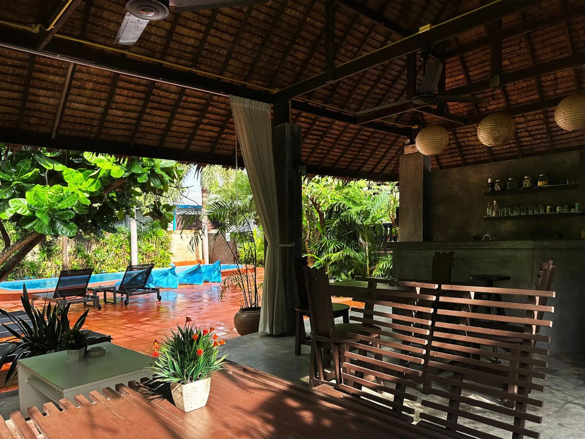 Espace extérieur ombragé avec un bar et des chaises longues près d'une piscine.