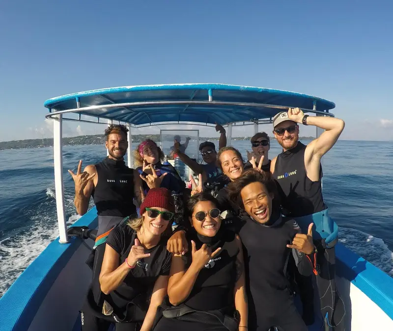 Groupe de personnes souriantes à bord d'un bateau en mer.
