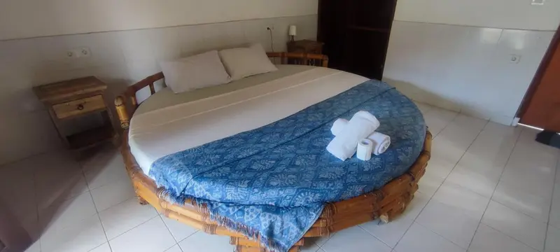 Une chambre lumineuse avec un grand lit rond en rotin.