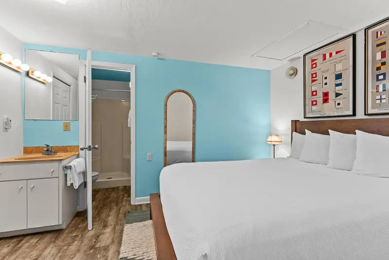 Une chambre lumineuse avec un lit double et un coin lavabo.