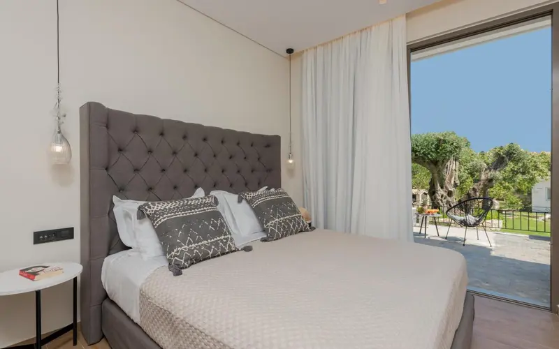 Une chambre lumineuse avec un grand lit et un accès à une terrasse.