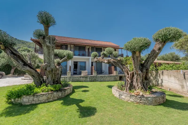 Bâtiment à deux étages avec des arbres taillés et une pelouse verdoyante.
