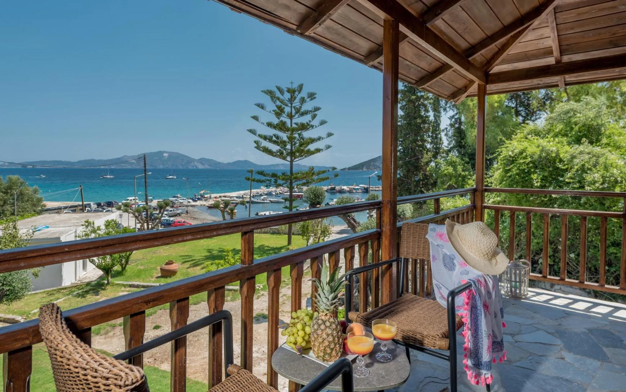 Une terrasse ombragée donne sur une vue mer et un port de plaisance.