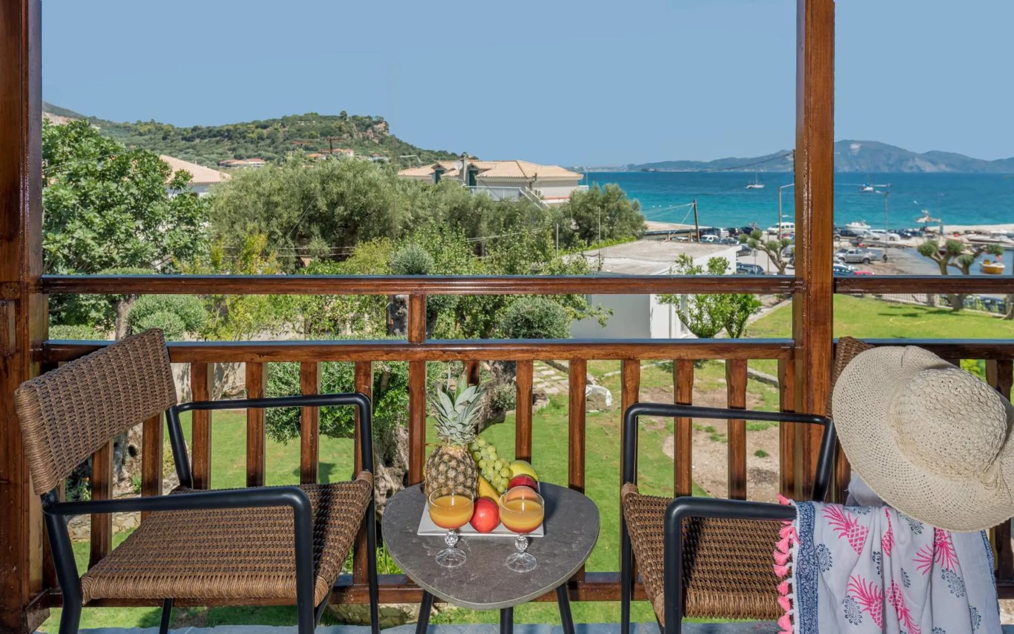 Une terrasse avec une table basse et des fauteuils offre une vue sur la mer et la végétation.