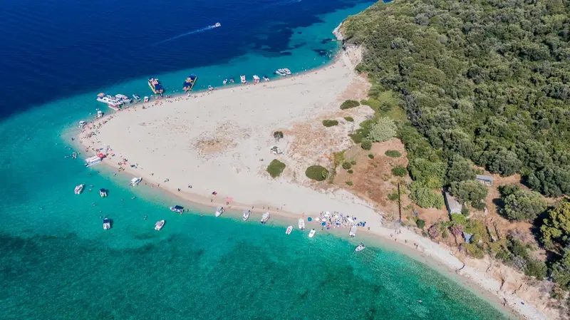 Vue aérienne d'une plage de sable fin bordée d'une eau turquoise et de quelques embarcations.