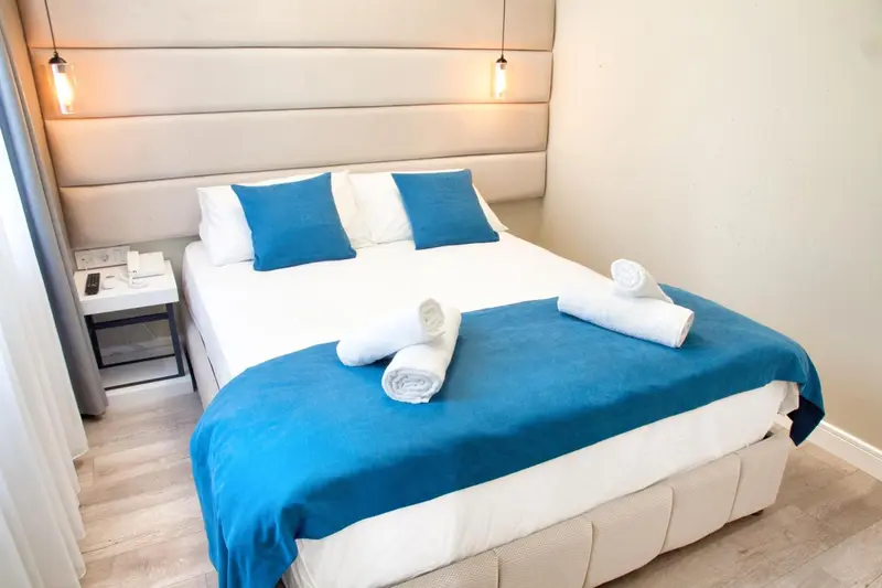 Un lit double est fait avec une couverture bleue et des oreillers turquoise.