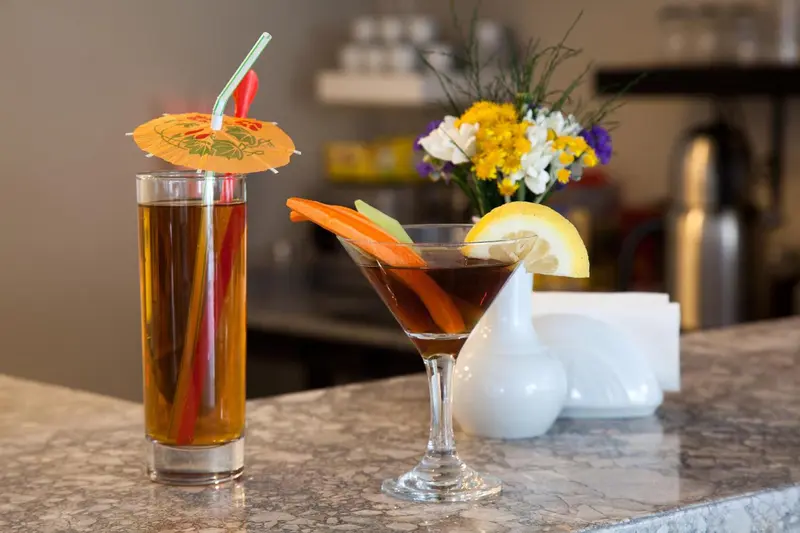 Deux cocktails colorés sont présentés sur un comptoir.