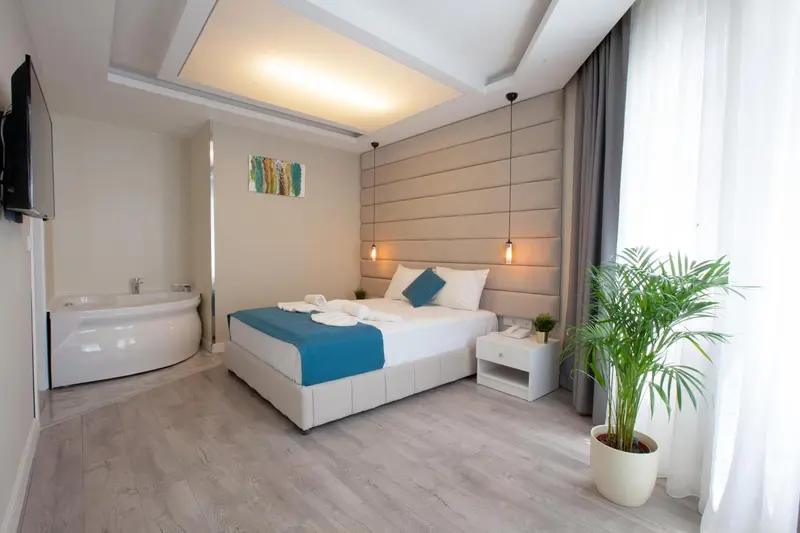 Une chambre lumineuse avec un grand lit et une baignoire surélevée.
