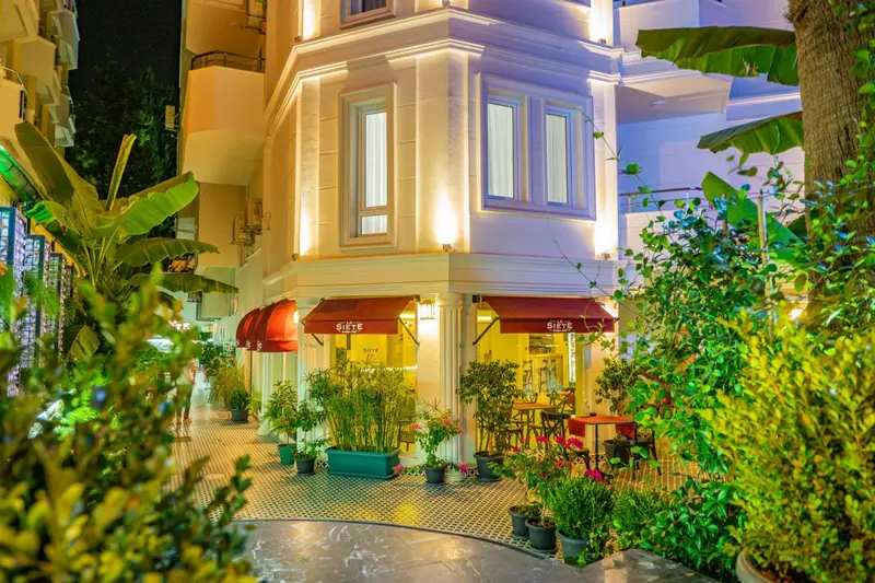 Façade d'un bâtiment éclairé avec des plantes et des tables.