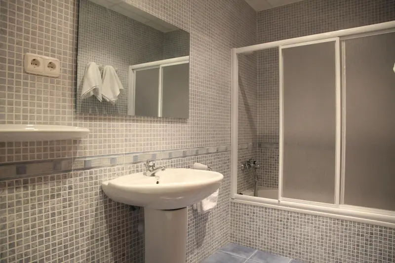 Une salle de bain carrelée avec lavabo et douche vitrée.