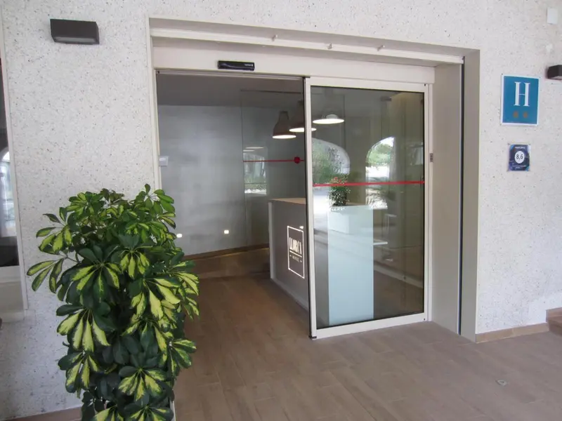 Entree d'un batiment avec un comptoir d'accueil visible a travers une verriere.
