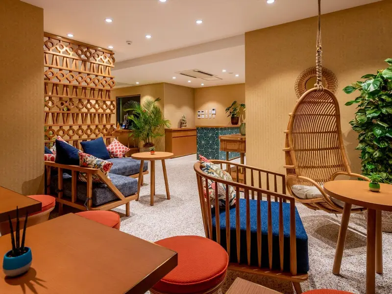 Espace de détente intérieur avec mobilier en bois et plantes vertes.