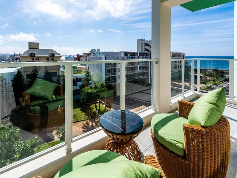 Terrasse avec mobilier en osier et vue sur la ville et la mer.