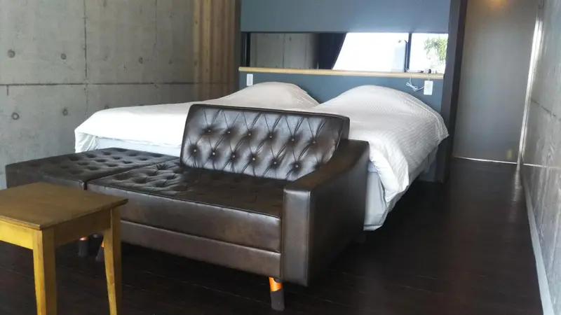 Une chambre avec un lit double et un canapé en cuir noir.