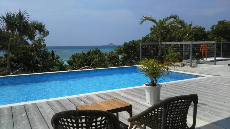 Terrasse avec piscine et mobilier de jardin face à la mer.