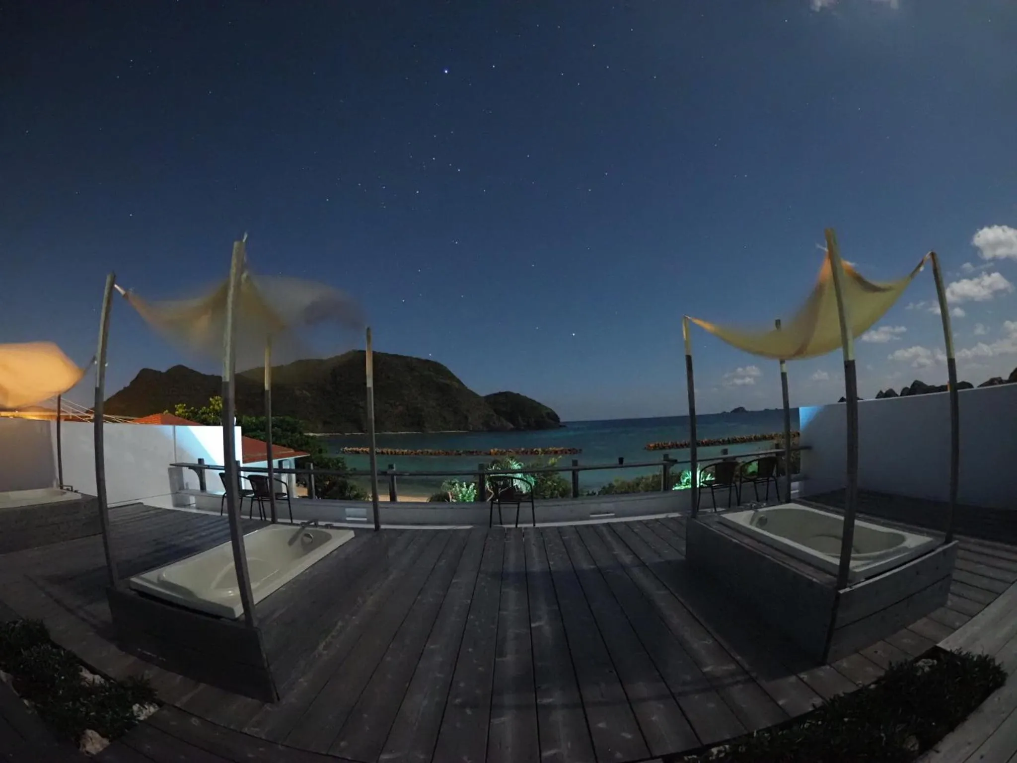 Terrasse avec mobilier d'extérieur et vue sur la mer au crépuscule.