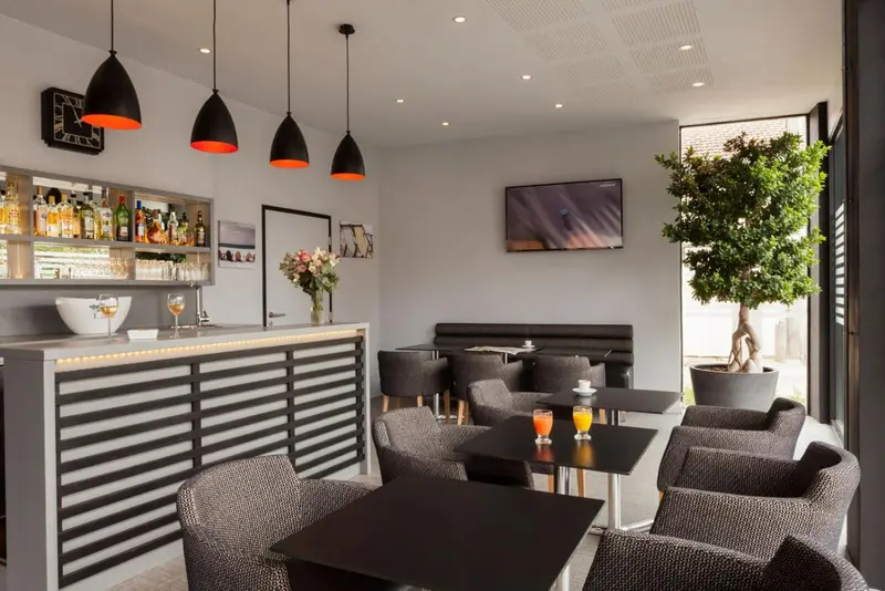 Un espace de bar avec des tabourets au comptoir et des tables basses.