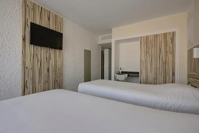Une chambre lumineuse avec un grand lit et un téléviseur mural.