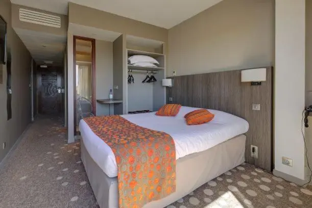 Une chambre lumineuse avec un grand lit recouvert d'une courtepointe orange et de coussins.