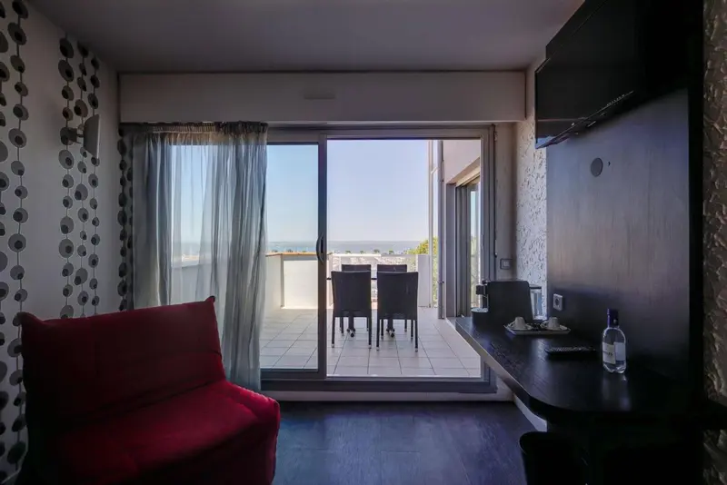 Une pièce lumineuse s'ouvre sur une terrasse avec vue sur la mer.