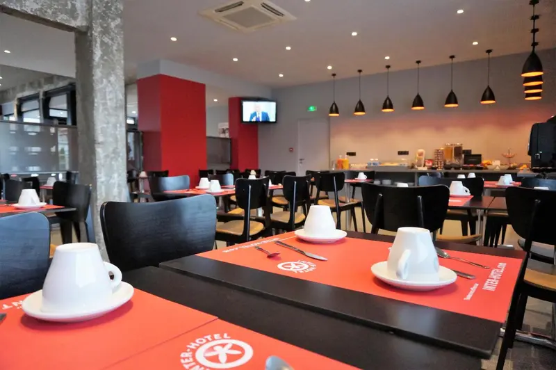 Une salle lumineuse avec des tables dressées pour le petit-déjeuner.