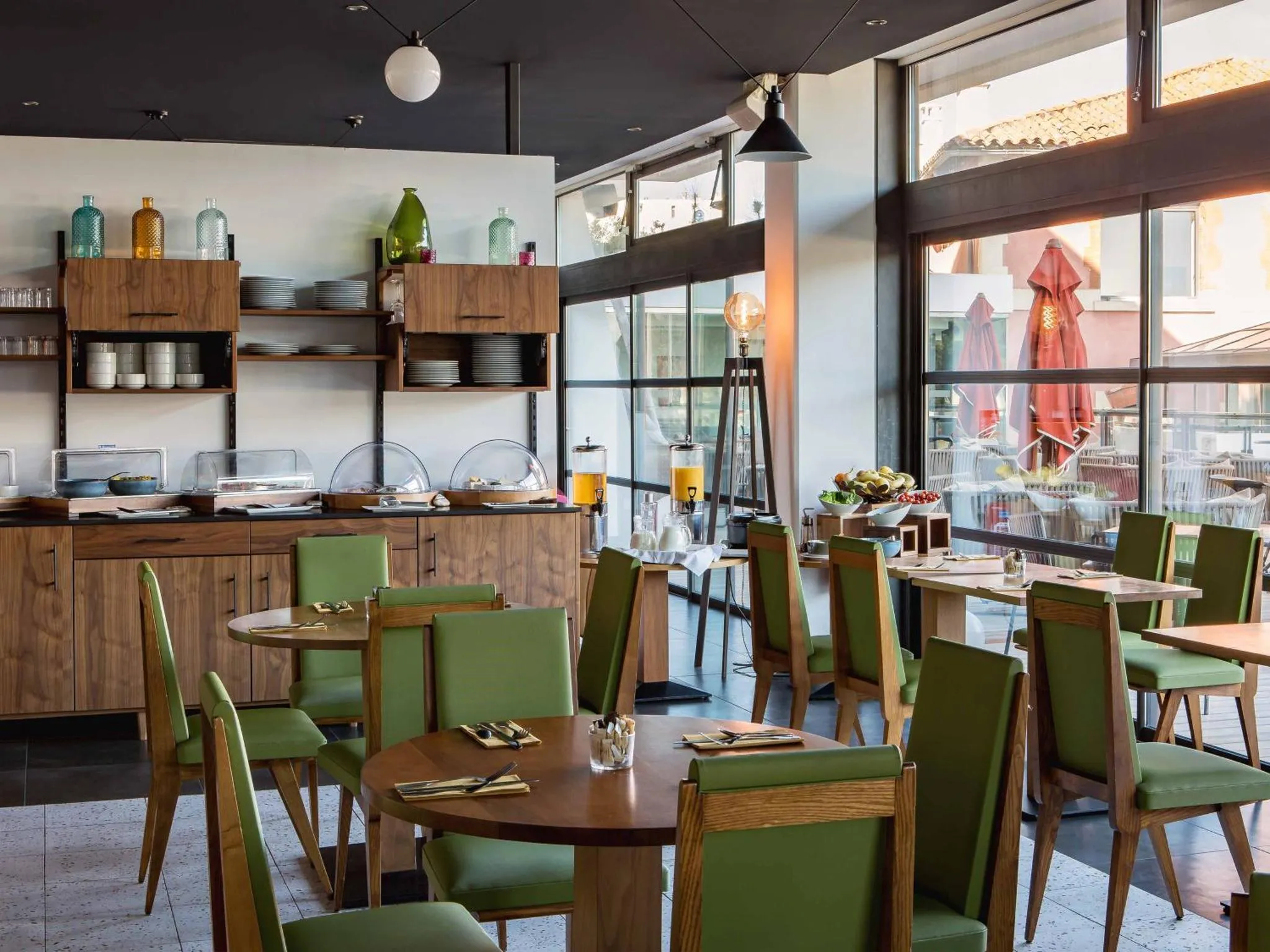 Une salle lumineuse avec des tables vertes et des buffets de nourriture.