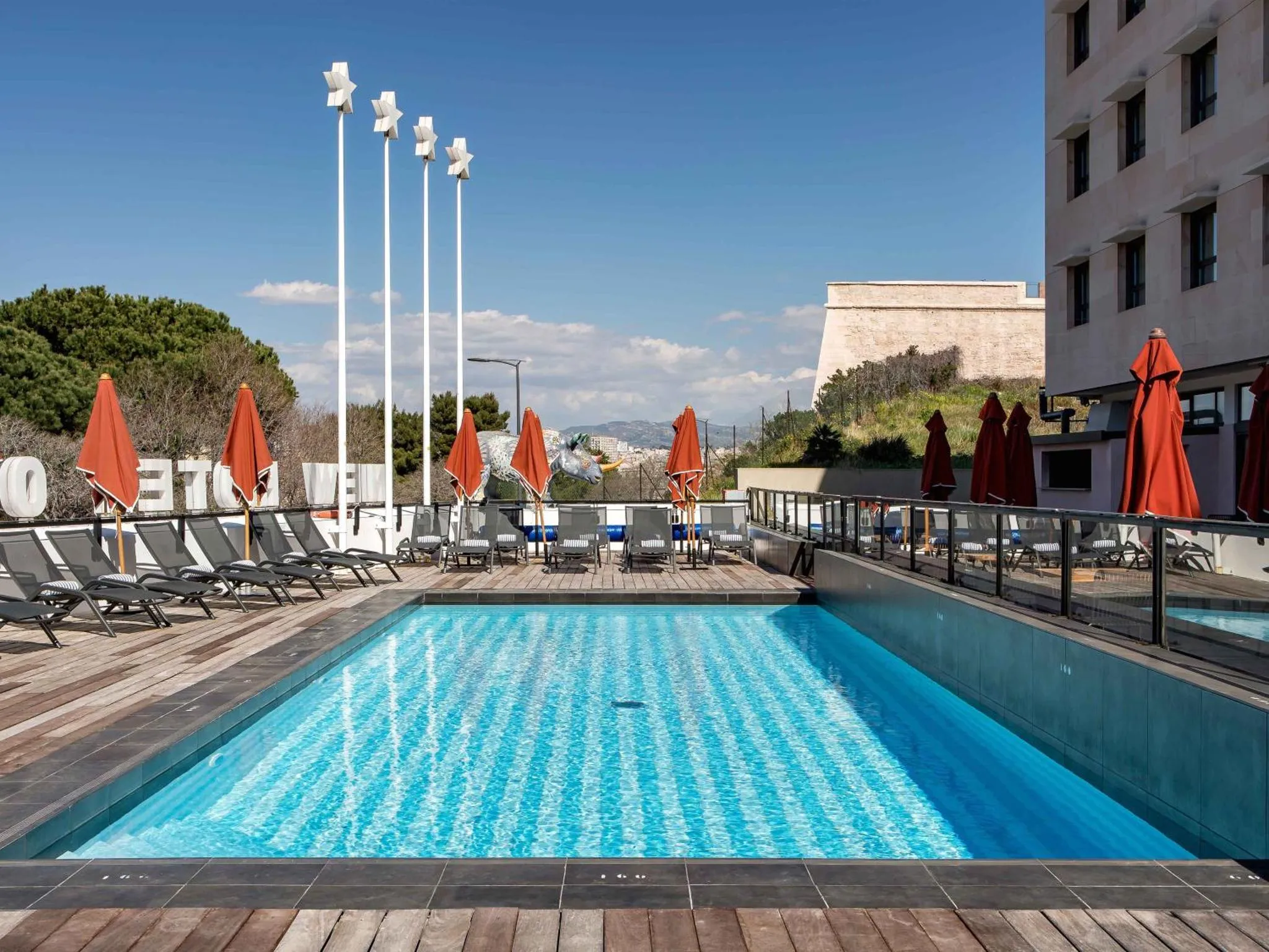 Terrasse avec piscine et chaises longues ensoleillées.