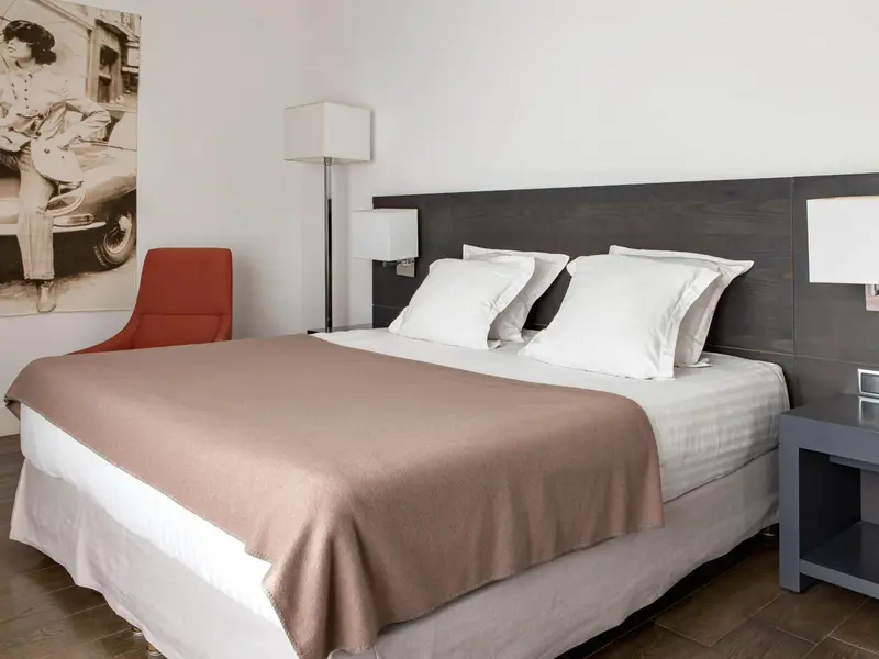 Une chambre d'hôtel moderne avec un grand lit et un fauteuil rouge.