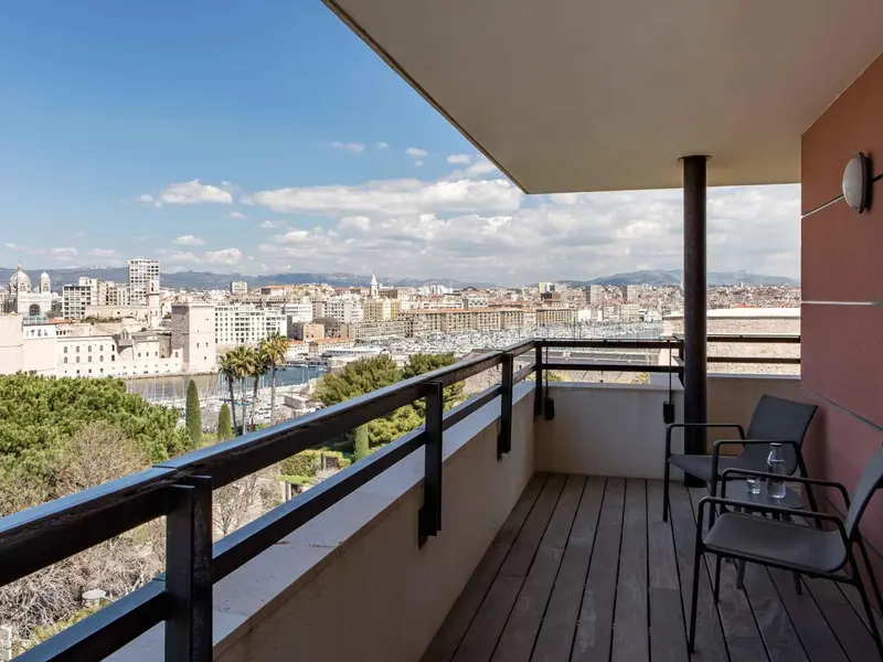 Terrasse avec mobilier d'extérieur donnant sur une vue urbaine et côtière.