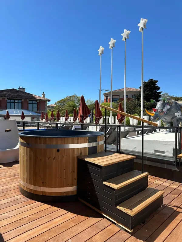 Terrasse en bois avec jacuzzi et parasols rouges.